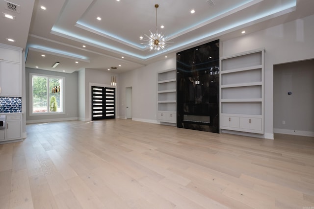 221 Abington Cir, Little Rock, AR 72223 - unfurnished living room with light wood-type flooring, an inviting chandelier, baseboards, visible vents, and built in shelves