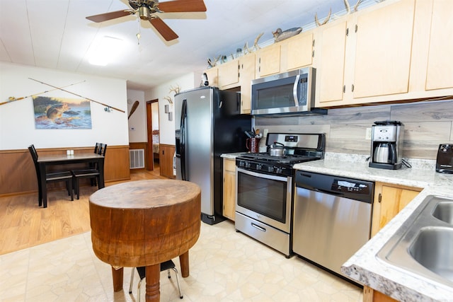 kitchen with wainscoting, visible vents, ceiling fan, stainless steel appliances, and a sink