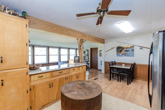 kitchen featuring light wood-type flooring, light brown cabinets, light stone counters, freestanding refrigerator, and a ceiling fan