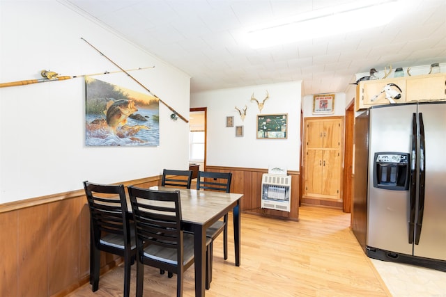 dining area featuring light wood-style floors, ornamental molding, wainscoting, wooden walls, and heating unit