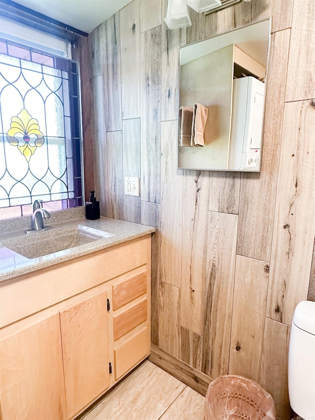 bathroom with wood walls, vanity, and toilet