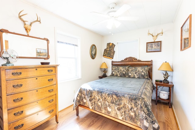bedroom featuring light wood-style flooring, crown molding, ceiling fan, and baseboards