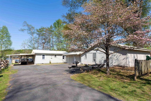 single story home featuring a carport, fence, and driveway