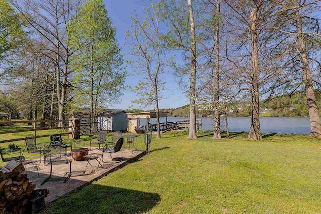 view of yard featuring a shed, a water view, an outdoor fire pit, a patio area, and an outdoor structure