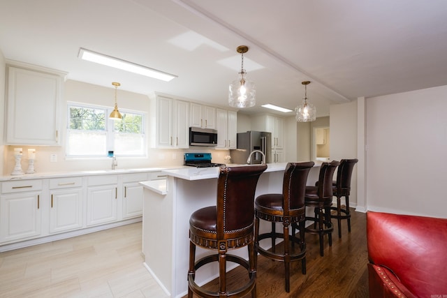 104 Dickson Dr, Little Rock, AR 72207 - kitchen with hanging light fixtures, a sink, light countertops, appliances with stainless steel finishes, and an island with sink