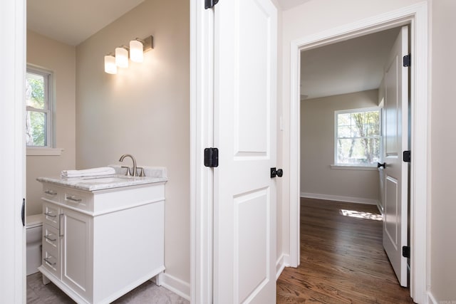 104 Dickson Dr, Little Rock, AR 72207 - bathroom featuring wood finished floors, vanity, baseboards, and a healthy amount of sunlight