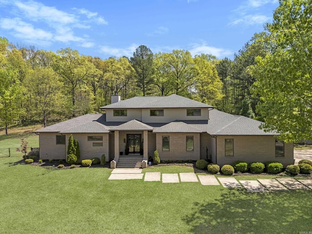 prairie-style house featuring a front yard, french doors, a chimney, and a shingled roof