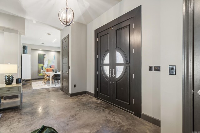 entrance foyer with finished concrete floors, baseboards, and a notable chandelier
