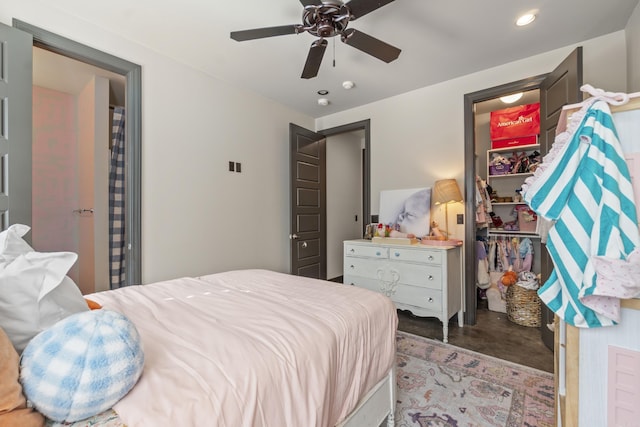 bedroom featuring a closet, recessed lighting, a walk in closet, ceiling fan, and concrete flooring