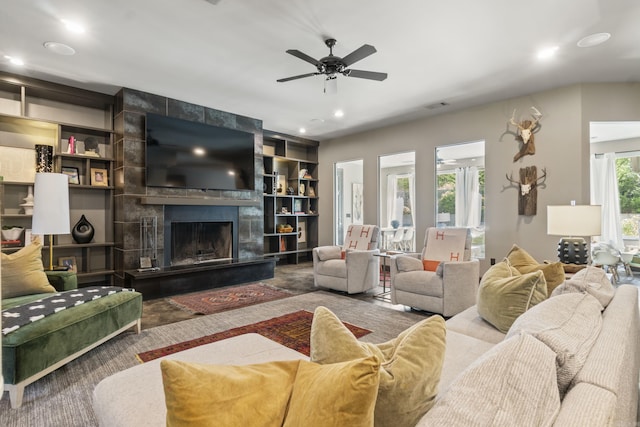 living room featuring a large fireplace, built in features, a ceiling fan, and recessed lighting