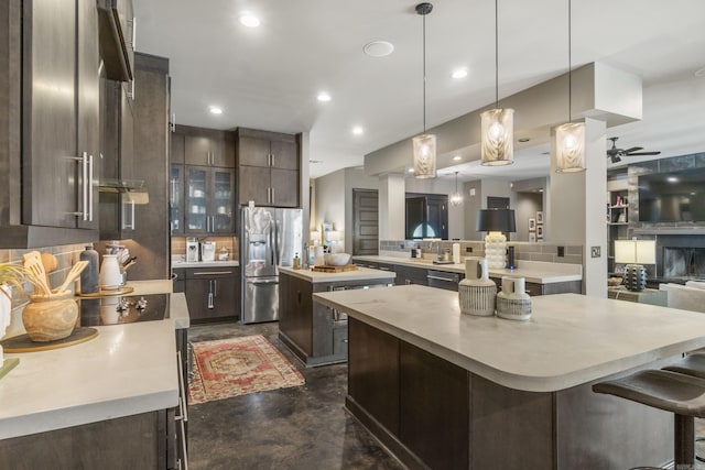 kitchen with dark brown cabinetry, a kitchen island, light countertops, and stainless steel appliances