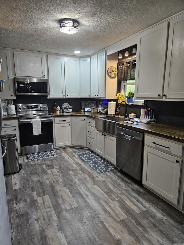 1139 Crescent Dr, Mena, AR 71953 - kitchen featuring stainless steel appliances, white cabinetry, wood finished floors, and dark countertops