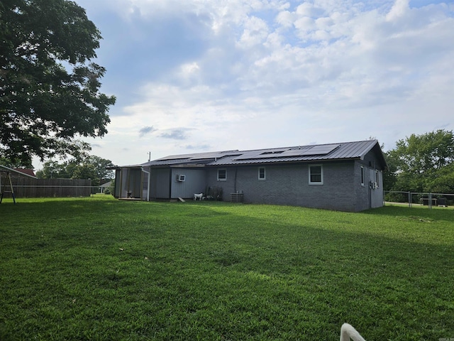 1139 Crescent Dr, Mena, AR 71953 - rear view of property featuring roof mounted solar panels, a yard, metal roof, a fenced backyard, and cooling unit