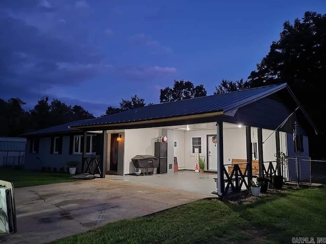 1139 Crescent Dr, Mena, AR 71953 - back of property with concrete driveway, a patio, metal roof, fence, and a lawn