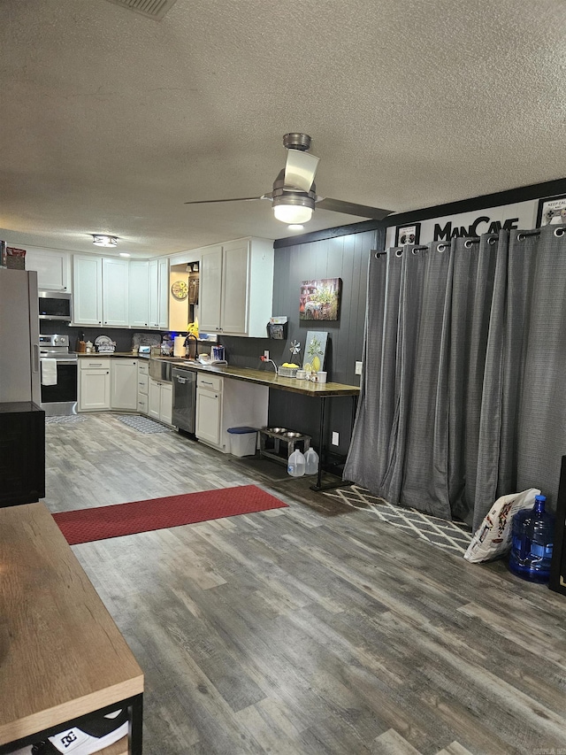 1139 Crescent Dr, Mena, AR 71953 - kitchen with a textured ceiling, white cabinets, appliances with stainless steel finishes, wood finished floors, and dark countertops