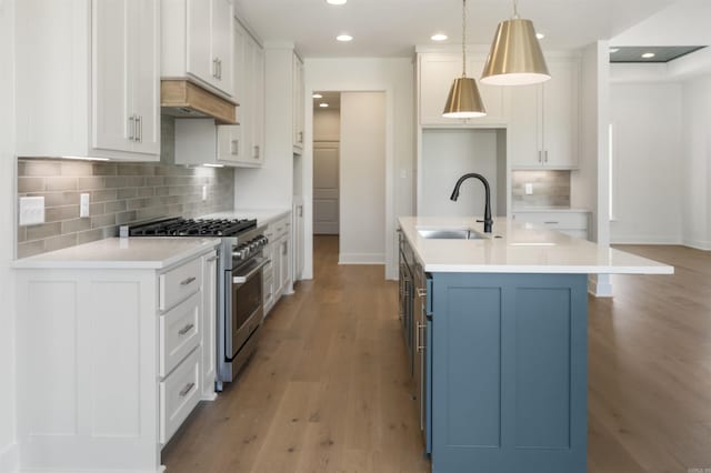 kitchen featuring light wood-style floors, white cabinetry, a sink, baseboards, and stainless steel range