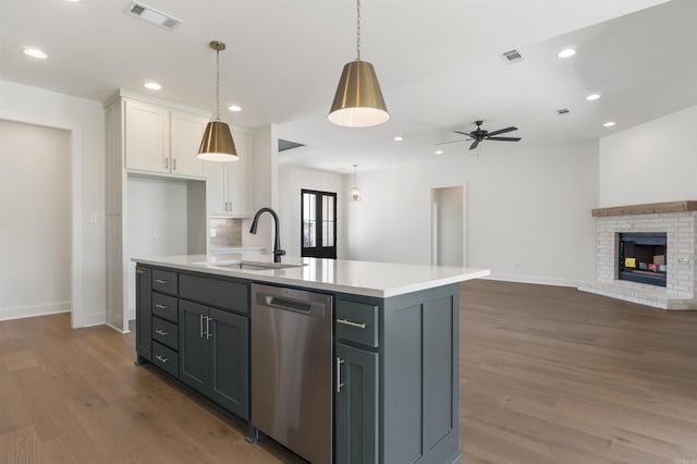 kitchen featuring stainless steel dishwasher, white cabinetry, visible vents, light countertops, and a sink