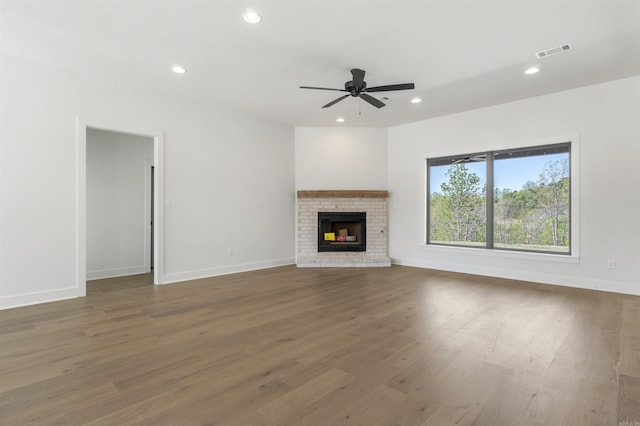 unfurnished living room with a fireplace, a ceiling fan, visible vents, recessed lighting, and wood finished floors
