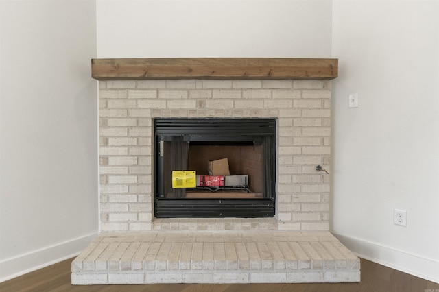 interior details featuring a fireplace with raised hearth, baseboards, and wood finished floors