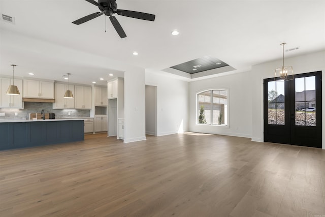 unfurnished living room featuring visible vents, a wealth of natural light, and light wood-style floors