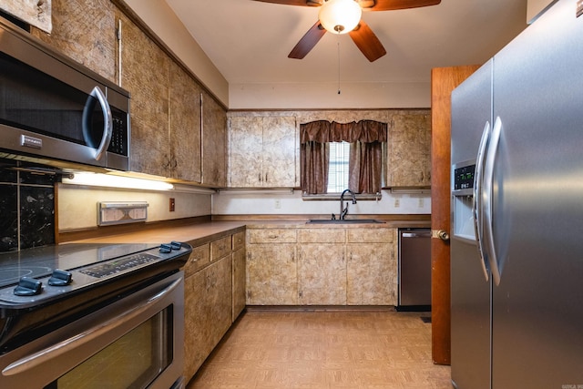 kitchen with appliances with stainless steel finishes, a sink, a ceiling fan, and light floors