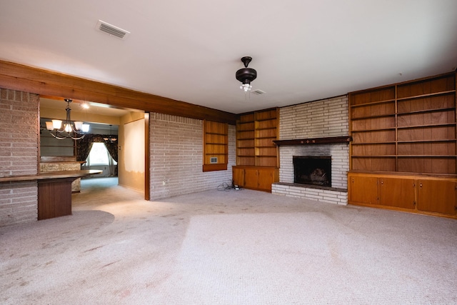 unfurnished living room with visible vents, brick wall, a brick fireplace, a chandelier, and carpet floors