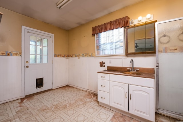bathroom featuring a healthy amount of sunlight, vanity, and a wainscoted wall