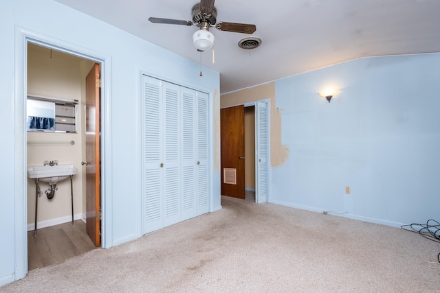 unfurnished bedroom with carpet flooring, visible vents, a closet, and ensuite bath