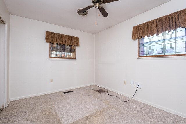 carpeted spare room with visible vents, baseboards, and ceiling fan