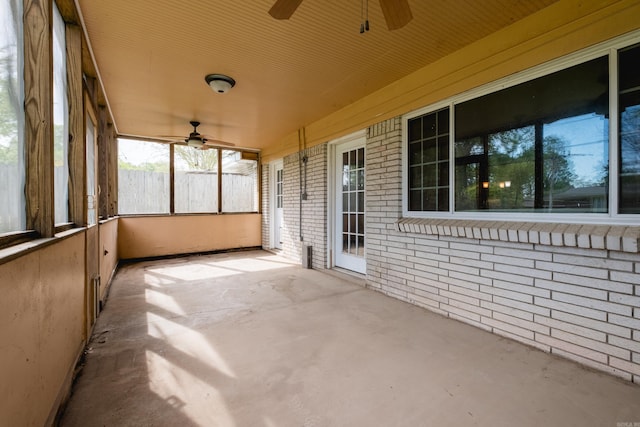 unfurnished sunroom featuring ceiling fan and a wealth of natural light
