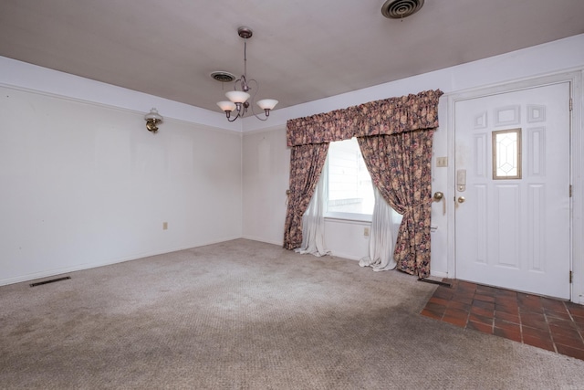 foyer entrance with visible vents, carpet flooring, and a notable chandelier