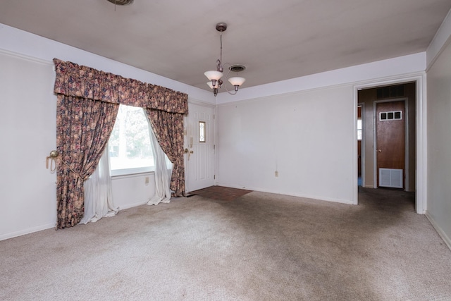 carpeted spare room featuring an inviting chandelier, baseboards, and visible vents