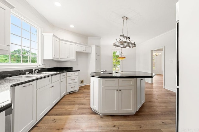 kitchen featuring ornamental molding, white cabinets, a sink, light wood-style flooring, and pendant lighting
