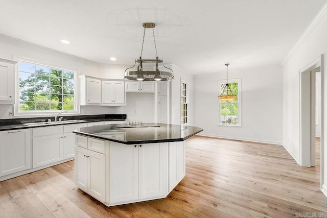 kitchen featuring a sink, crown molding, plenty of natural light, light wood-style floors, and white cabinetry