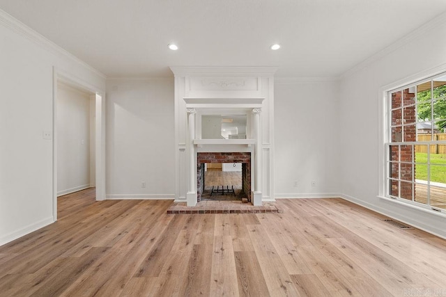 unfurnished living room with a brick fireplace, crown molding, light wood-type flooring, baseboards, and recessed lighting