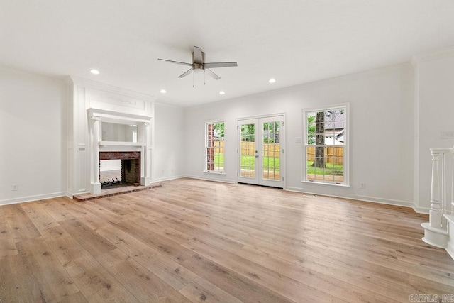 unfurnished living room with ceiling fan, a fireplace, light wood-style floors, ornamental molding, and baseboards