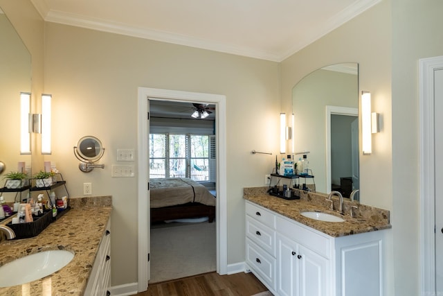 bathroom with two vanities, a sink, crown molding, and wood finished floors