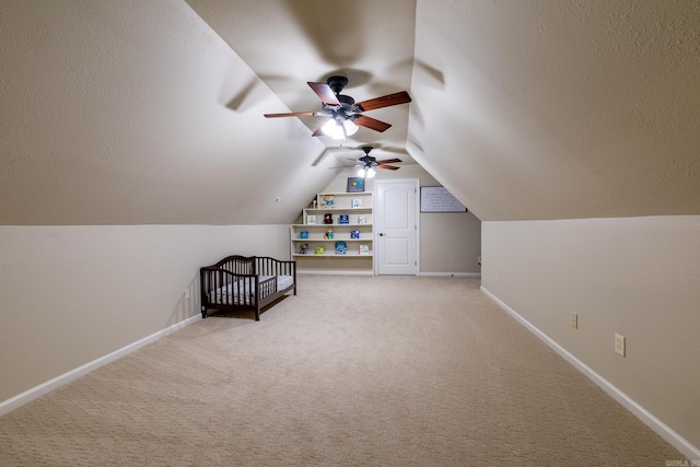 unfurnished bedroom with baseboards, ceiling fan, light colored carpet, and vaulted ceiling