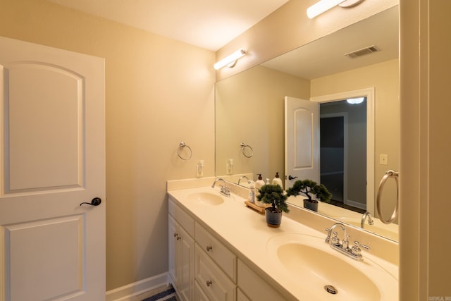 bathroom featuring baseboards, double vanity, a sink, and visible vents