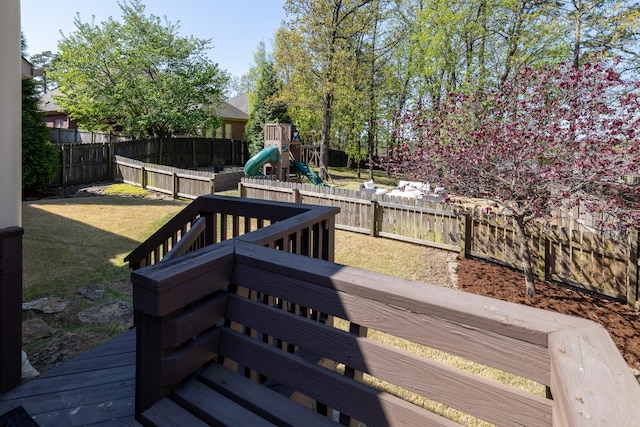 wooden deck featuring a fenced backyard, a playground, and a lawn