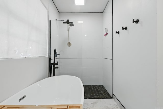 bathroom with a freestanding bath, marble finish floor, and a tile shower