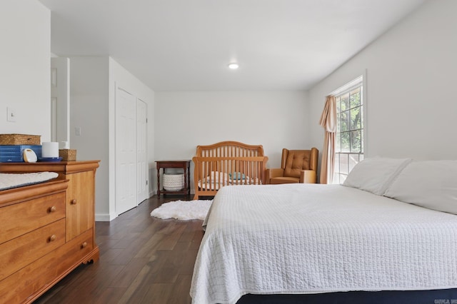 bedroom with dark wood-type flooring, a closet, and baseboards