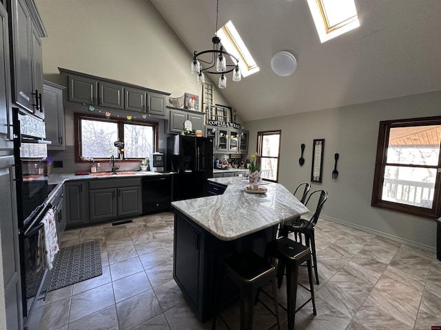 kitchen with high vaulted ceiling, black appliances, a kitchen island, and a wealth of natural light