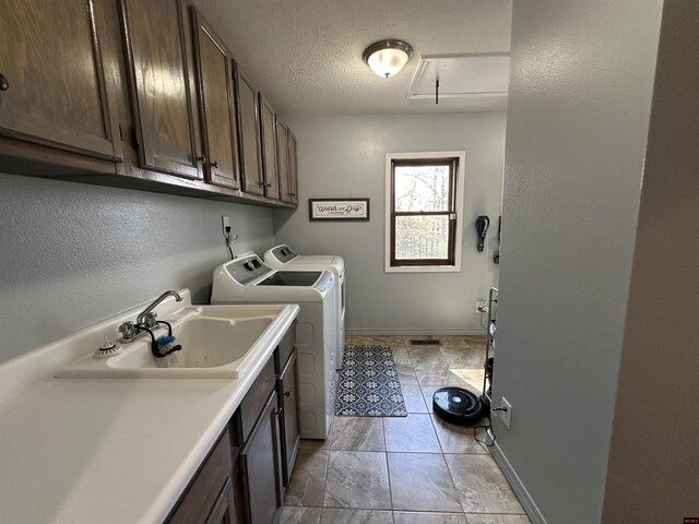 washroom featuring baseboards, a sink, attic access, cabinet space, and washer and clothes dryer