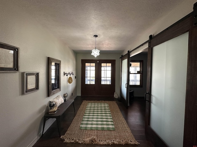 entryway featuring dark wood-type flooring, a textured ceiling, baseboards, and a barn door