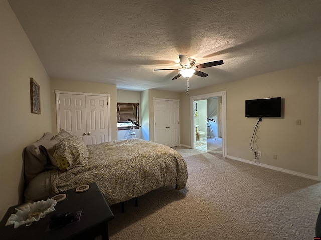 bedroom featuring baseboards, two closets, ceiling fan, a textured ceiling, and light colored carpet