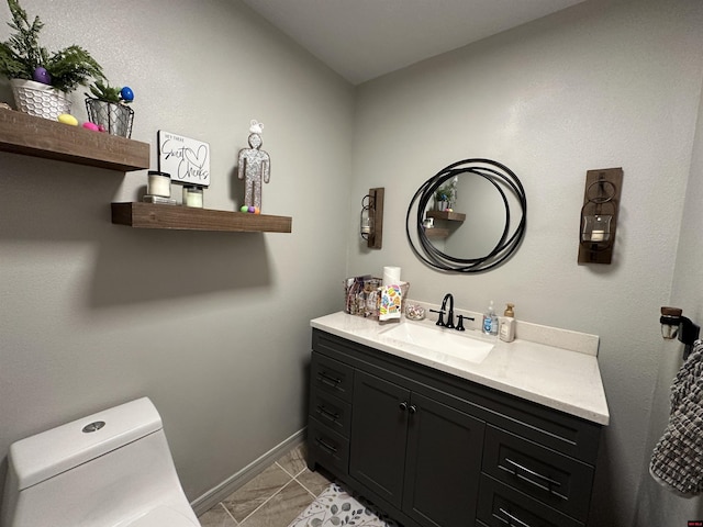 bathroom featuring vanity, marble finish floor, baseboards, and toilet