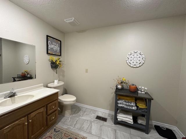 bathroom featuring visible vents, toilet, vanity, and a textured ceiling