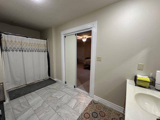 bathroom featuring vanity, marble finish floor, baseboards, and curtained shower