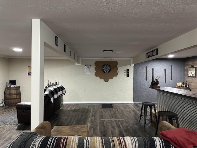 interior space featuring a textured ceiling, wood finished floors, a textured wall, and baseboards